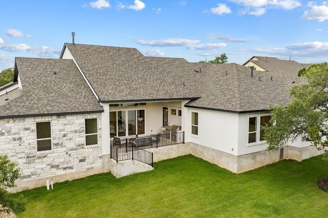Back of property featuring a shingled roof, a yard, stone siding, and stucco siding | Image 37