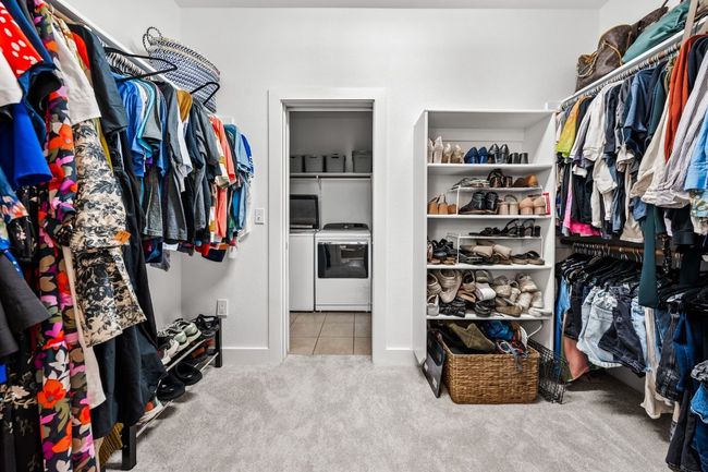 Walk in closet featuring carpet floors, tile patterned floors, and washer and clothes dryer | Image 16