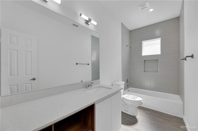 Full bathroom featuring wood-type flooring, vanity, toilet, and tiled shower / bath combo | Image 11
