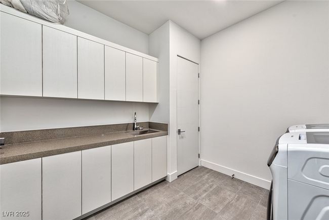 Laundry room with washing machine and clothes dryer, cabinet space, a sink, baseboards, and wet bar | Image 14
