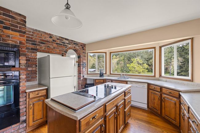 Kitchen featuring black appliances, a warming drawer, a kitchen island, and brown cabinets | Image 13