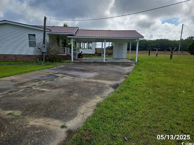 View of front of house with a front yard, driveway, a porch, an attached carport, and metal roof | Image 4