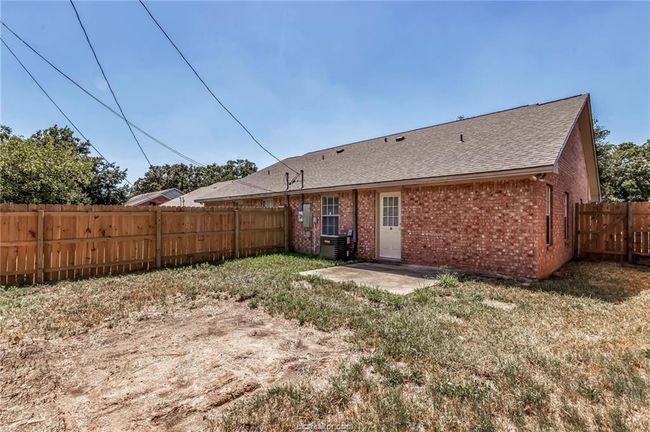 Back of property with brick siding, a fenced backyard, a shingled roof, and a patio area | Image 15