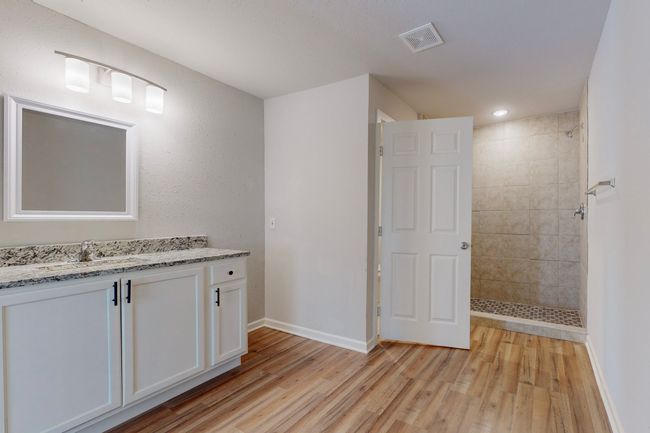 Bathroom with vanity, hardwood / wood-style flooring, and a tile shower | Image 25