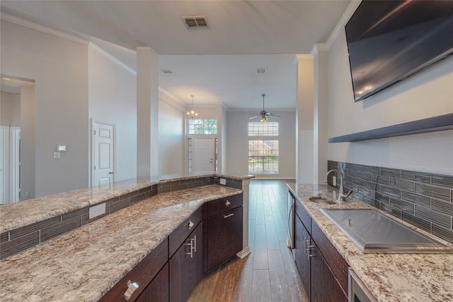 Kitchen with a sink, hardwood / wood-style flooring, ornamental molding, dark brown cabinets, and a ceiling fan | Image 13