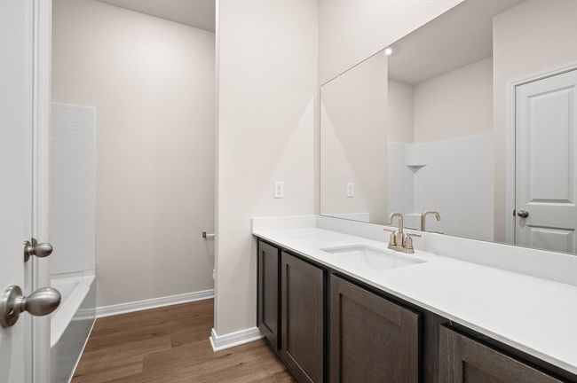 Bathroom with vanity, wood finished floors, baseboards, a bathtub, and a shower | Image 8
