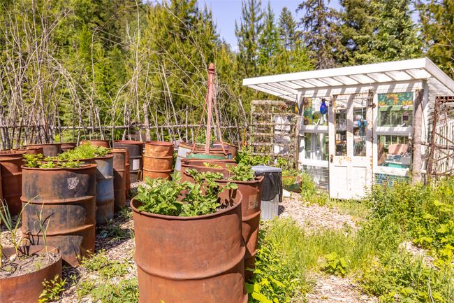 View of yard featuring a greenhouse, a vegetable garden, and an outbuilding | Image 89
