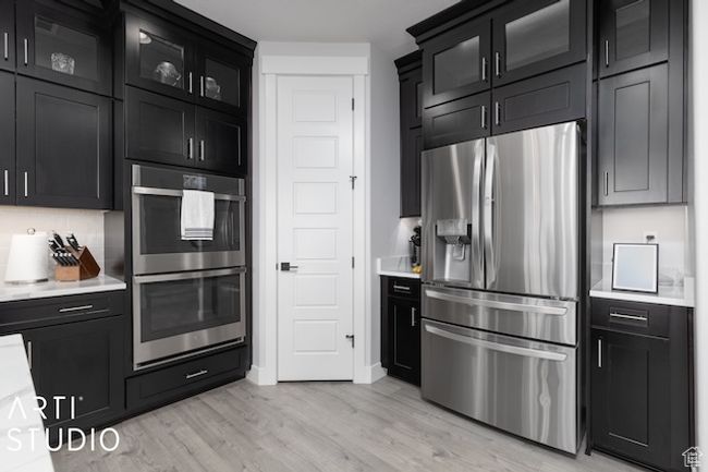 Kitchen with glass insert cabinets, appliances with stainless steel finishes, light countertops, and dark cabinets | Image 13