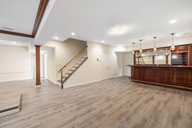 Unfurnished living room with stairs, light wood finished floors, recessed lighting, crown molding, and baseboards | Image 19