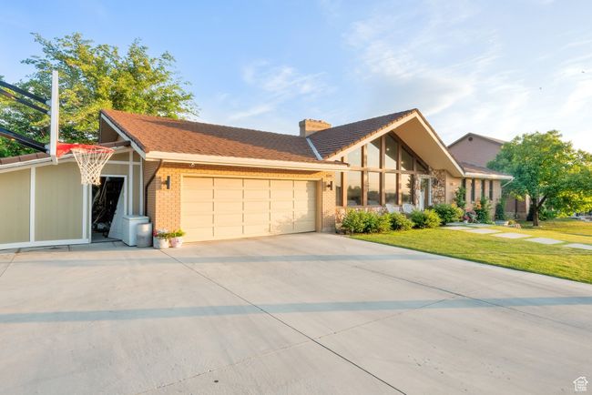View of front of home with an attached garage, brick siding, a chimney, and concrete driveway | Image 40