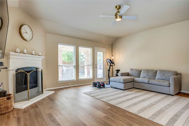 Living area with ceiling fan, a fireplace with raised hearth, wood finished floors, lofted ceiling, and baseboards | Image 21