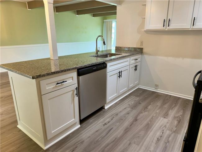 Kitchen with stainless steel dishwasher, white cabinets, a sink, light wood-style floors, and a peninsula | Image 4