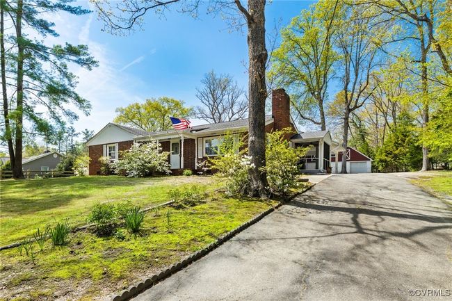Ranch-style home featuring aphalt driveway, a chimney, a front yard, brick siding, and a garage | Image 4