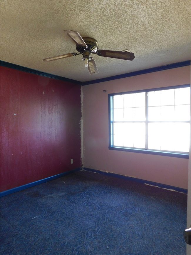 Carpeted empty room featuring a textured ceiling and ceiling fan | Image 25