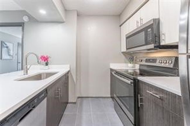 Kitchen featuring stainless steel appliances, light countertops, tile patterned floors, and white cabinets | Image 13
