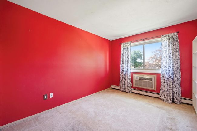 Empty room featuring baseboard heating, a wall mounted AC, baseboards, and carpet | Image 12