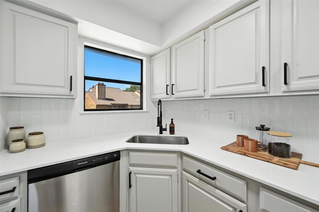Kitchen with dishwasher, backsplash, light countertops, and white cabinetry | Image 18