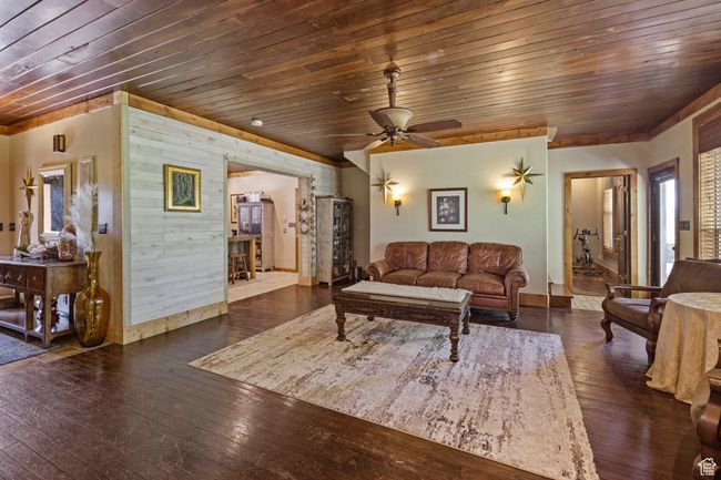Living room with wooden ceiling, hardwood / wood-style floors, baseboards, and ceiling fan | Image 6
