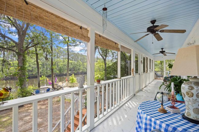 Porch with a water view, ceiling fan, and view of wooded area | Image 25
