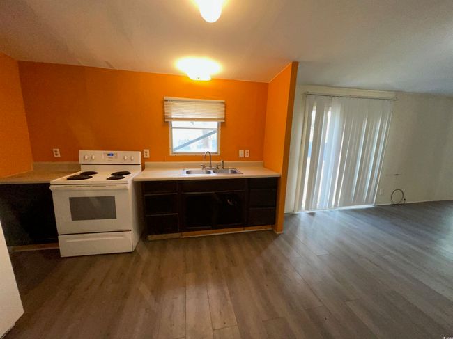 Kitchen with light countertops, a sink, electric range, and wood finished floors | Image 4