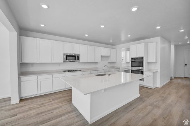 Kitchen featuring appliances with stainless steel finishes, a sink, recessed lighting, an island with sink, and white cabinetry | Image 4