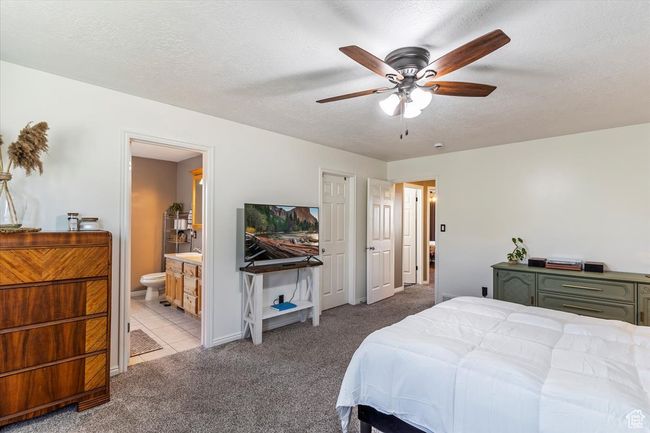 Bedroom with carpet, a textured ceiling, ensuite bath, baseboards, and ceiling fan | Image 13