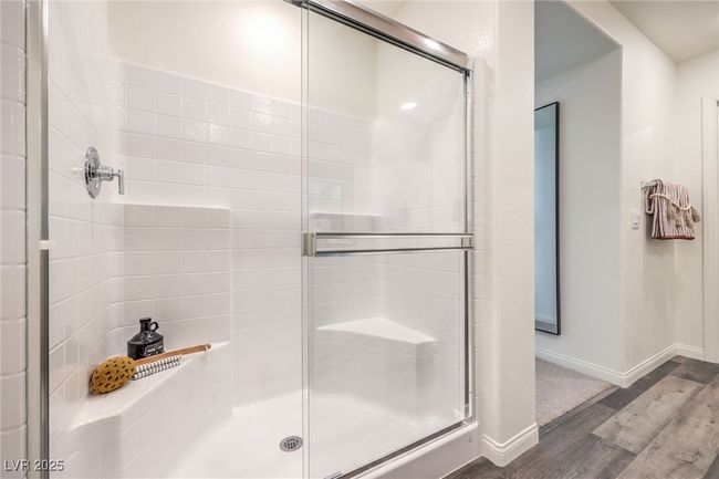Full bath featuring wood finished floors, a shower stall, and baseboards. Photo is representational only; actual home finishes may vary. | Image 26
