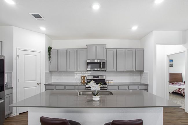 Kitchen with gray cabinets, a kitchen bar, stainless steel appliances, and visible vents | Image 17