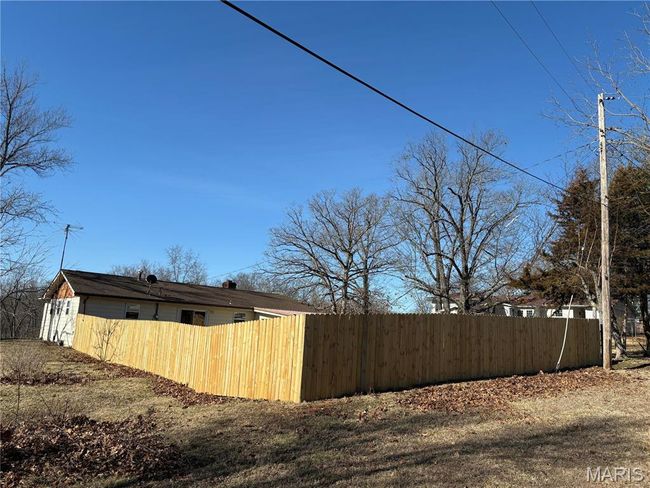 View of home's exterior with fence and a chimney | Image 7