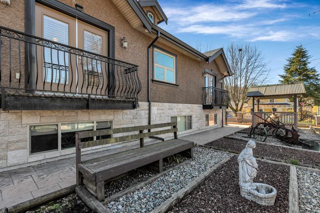 Rear view of property featuring a balcony, stone siding, stucco siding, and a patio area | Image 34