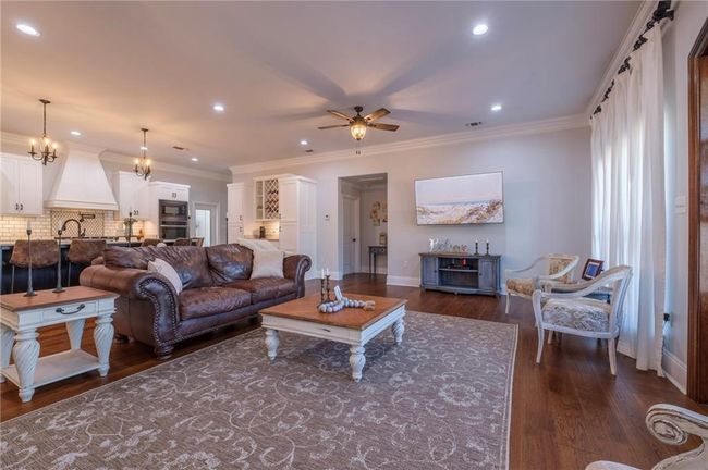 Living room featuring crown molding, dark hardwood / wood-style flooring, ceiling fan with notable chandelier, and sink | Image 6