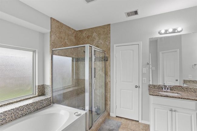 Welcome to your very own retreat! Relax after a long day in this wonderful Primary Bathroom with garden tub, and a glass enclosed shower. | Image 12