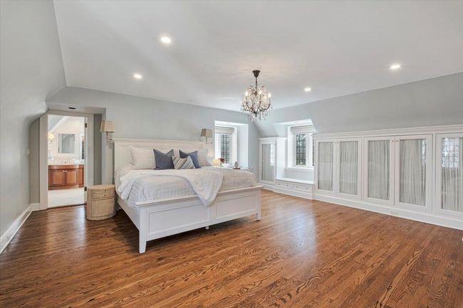 Spacious primary bedroom with baseboard molding, recessed lighting, lofted ceiling, wood floors and two walk-in closets plus built-in storage! | Image 12