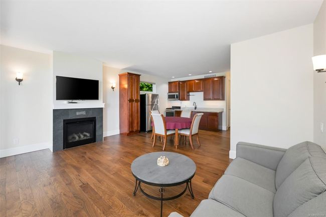 Living area with dark wood-style flooring, a tile fireplace, and recessed lighting | Image 58