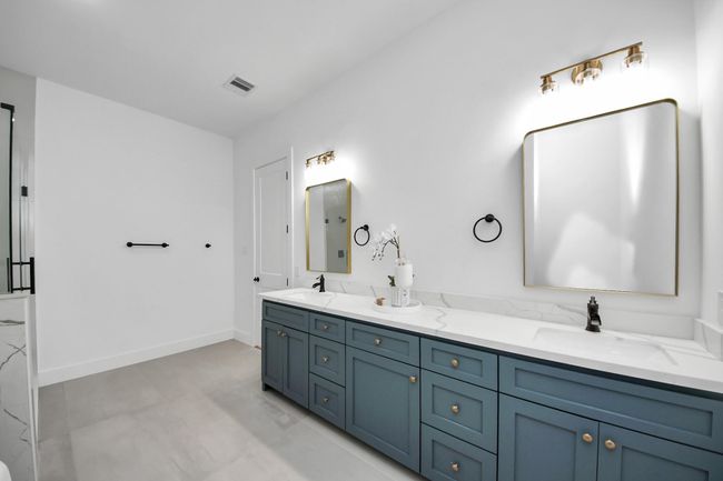 The primary bathroom features dual sinks, light countertops, freestanding tub, and separate shower. | Image 16
