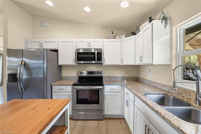 Kitchen with white cabinets, a sink, stainless steel appliances, and vaulted ceiling | Image 8