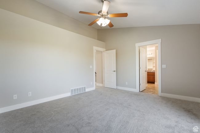 Unfurnished bedroom with lofted ceiling, light colored carpet, connected bathroom, and ceiling fan | Image 14