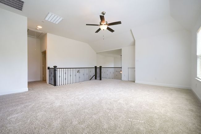 Unfurnished room featuring carpet, lofted ceiling, visible vents, attic access, and ceiling fan | Image 22
