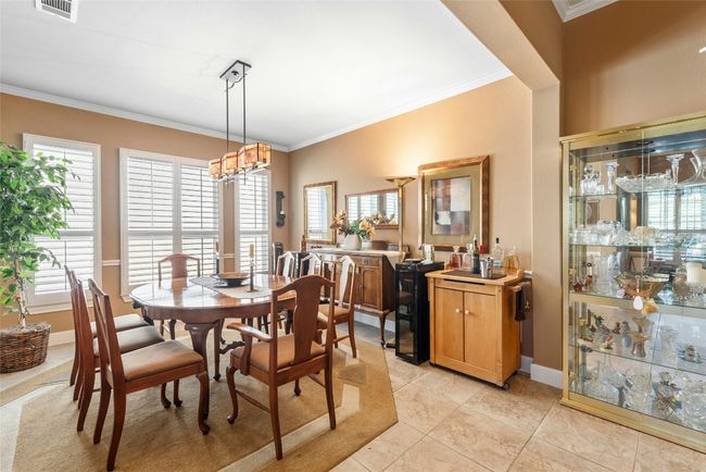 Dining area with crown molding, light tile patterned flooring, and a chandelier | Image 8