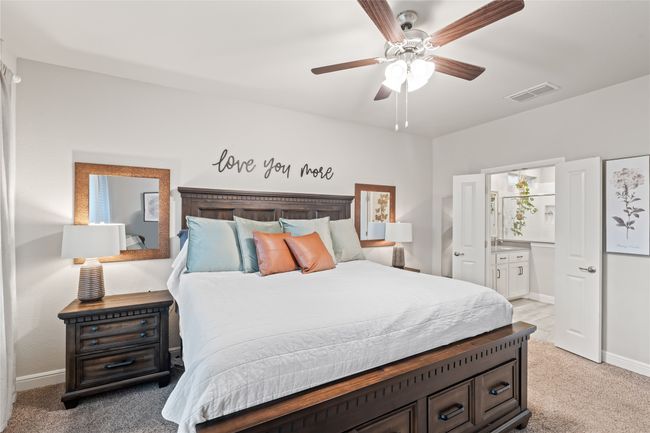 Bedroom with visible vents, connected bathroom, baseboards, ceiling fan, and light carpet | Image 17