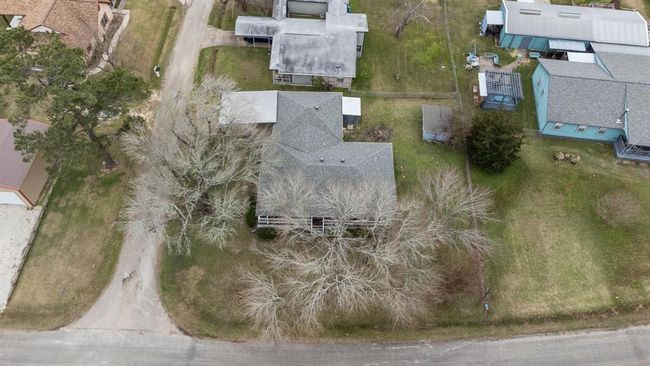 This aerial photo showcases the large yard on a corner lot. The property has mature trees and a driveway with a carport. | Image 43