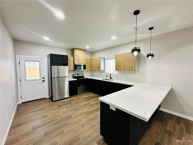 Kitchen with stainless steel appliances, a peninsula, a sink, dark cabinets, and recessed lighting | Image 4