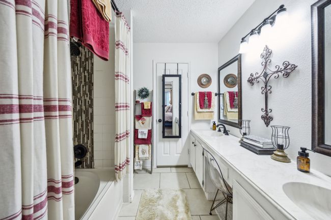 Full bathroom with double vanity, tile patterned flooring, a textured ceiling, and shower / bathtub combination with curtain | Image 21