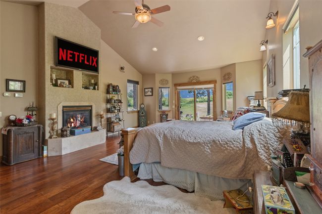 Bedroom with a large fireplace, wood finished floors, recessed lighting, high vaulted ceiling, and access to outside | Image 32