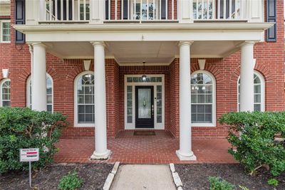 This home features impeccable curb appeal with a professionally landscaped pathway leading to the front door framed with transom windows that allows for natural light to illuminate the front foyer. The gorgeous bricked front porch is such a picturesque entryway! | Image 2