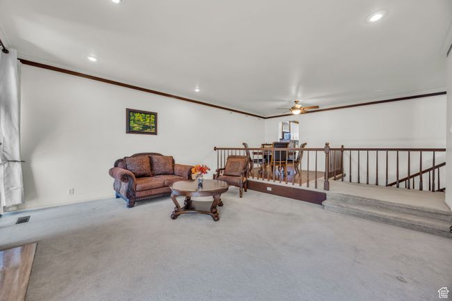 Carpeted living room with a ceiling fan, ornamental molding, visible vents, recessed lighting, and baseboards | Image 9