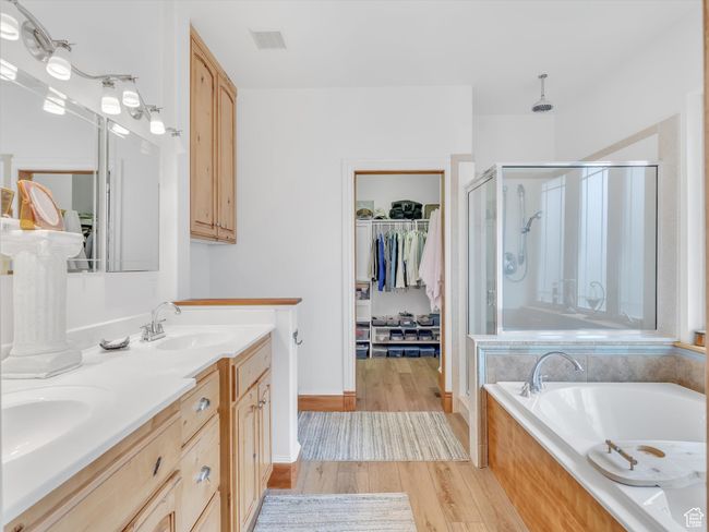 Full bath featuring a sink, visible vents, wood finished floors, a shower stall, and a garden tub | Image 22