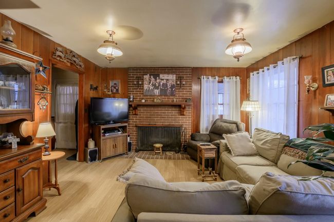 Family room is warmed by a cozy wood-burning, brick fireplace. | Image 7