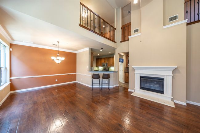 Living room with a chandelier, dark wood-style flooring, a glass covered fireplace, and ornamental molding | Image 10