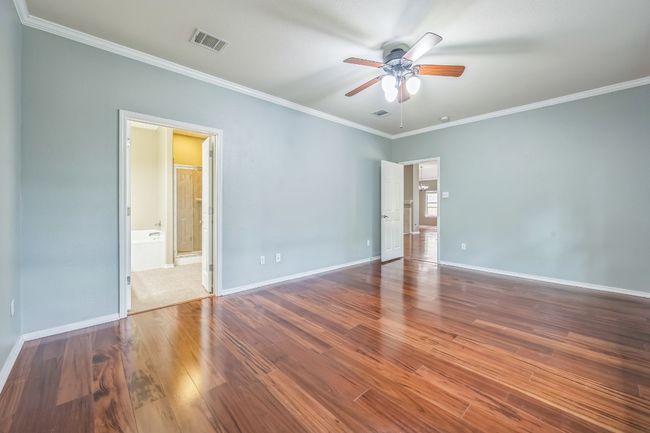 The private primary suite boasts tall ceilings, a ceiling fan, and a luxurious en-suite bathroom complete with a double vanity, garden soaking tub, separate shower, and a large walk-in closet. | Image 16
